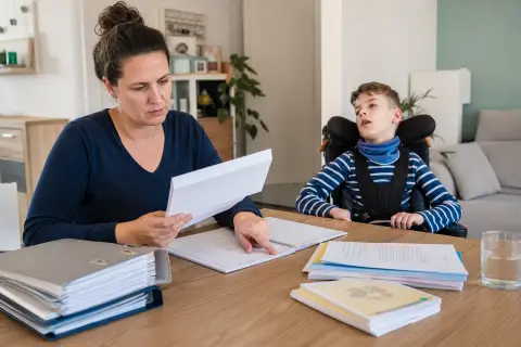 Pflegebegutachtung bei Kindern – Fristen „Pflegebegutachtung bei Kindern – Fristen“: Eltern und eine Fachberaterin besprechen zu Hause die Unterstützung eines pflegebedürftigen Kindes.