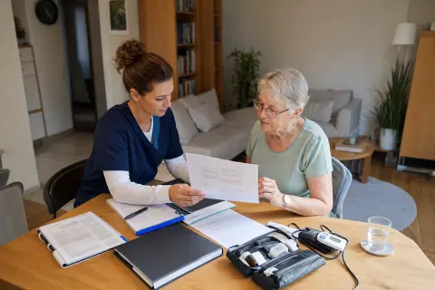 „Häusliche Krankenpflege: Verordnung und Genehmigung“: Eine Pflegefachperson bespricht mit einer pflegebedürftigen Person die weitere Versorgung nach einer Behandlung.