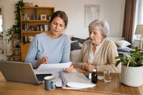 Pflegeunterstützungsgeld im akuten Pflegefall „Pflegeunterstützungsgeld im akuten Pflegefall“: Eine pflegende Angehörige prüft Unterlagen zur Vereinbarkeit von Beruf, Absicherung und Pflege.