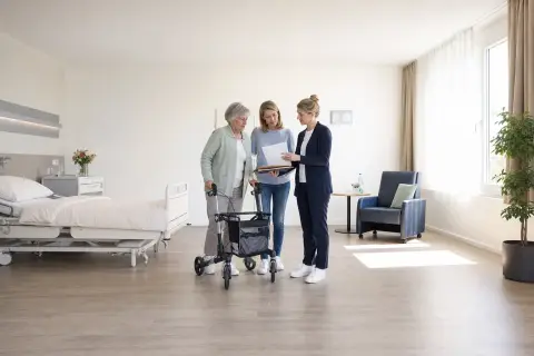 Rehabilitation nach Krankenhaus – Unterlagen „Rehabilitation nach Krankenhaus – Unterlagen“: Eine Pflegefachperson bespricht mit einer pflegebedürftigen Person die weitere Versorgung nach einer Behandlung.